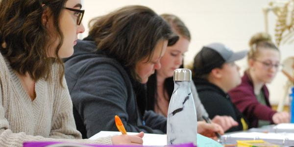 Students taking notes in classroom.