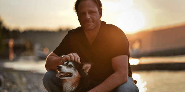 Brandon Niwa kneeling with his dog.
