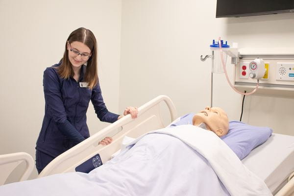 A young Health Care Aide student lowers hospital bed in a Medicine Hat College lab.