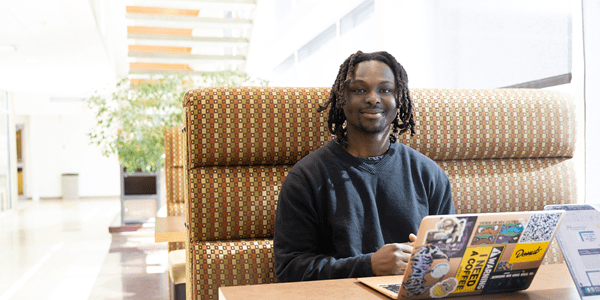 A smiling student sitting in a booth with his computer to study
