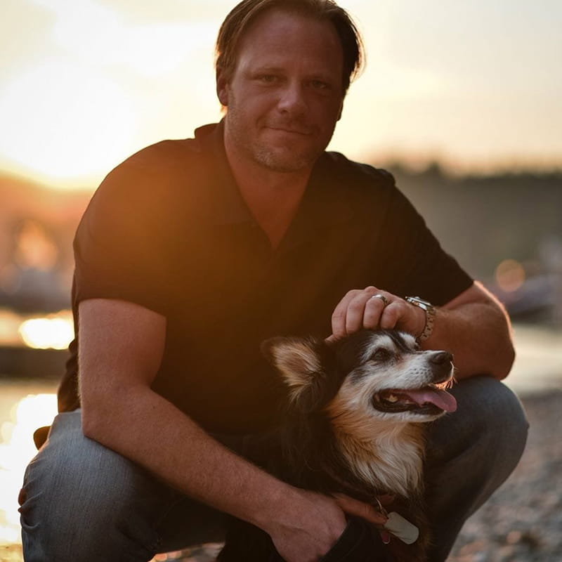 Brandon Niwa kneeling with his dog.