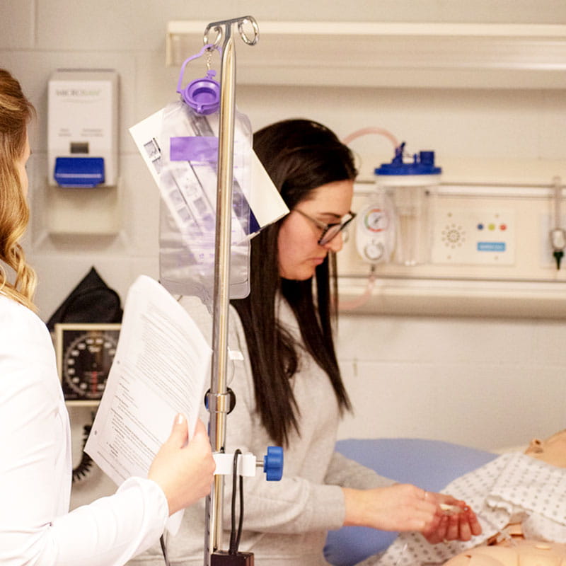 Nursing student practices skills in lab.